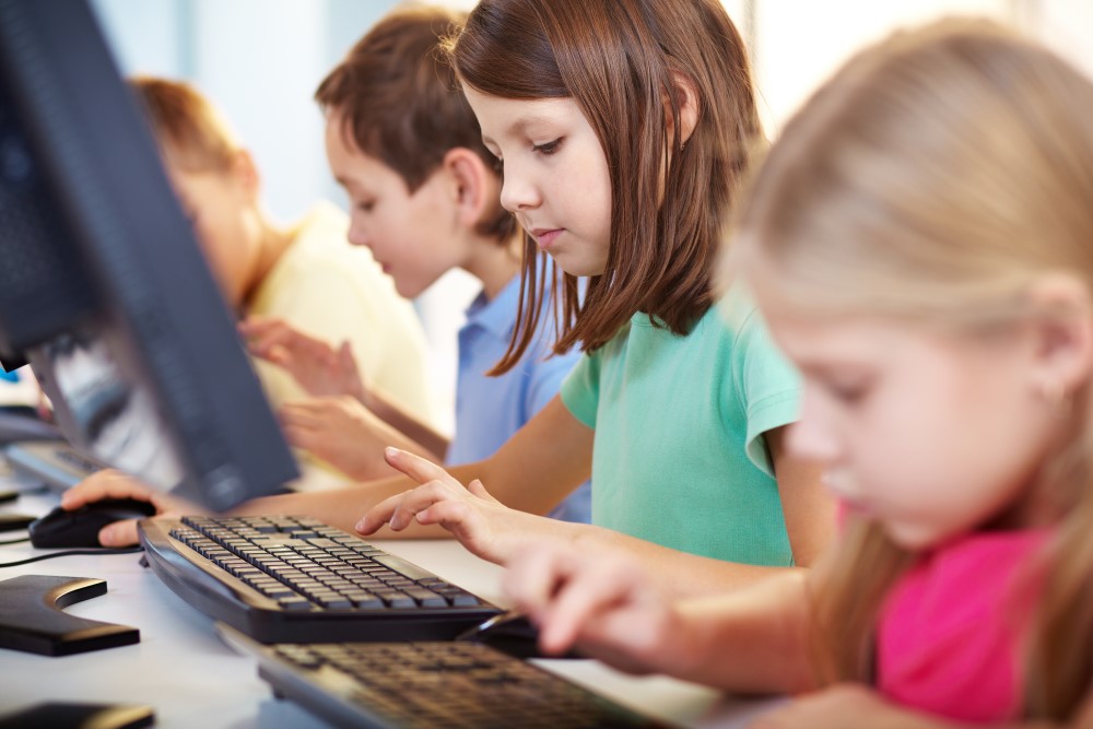 a picture of kids lined up using computers, as if conducting computerized testing